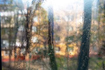 view from the apartment window to the street through the glass in wet droplets of water.