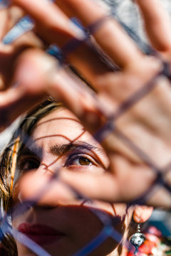 Young Colombian woman looking up with hands near on colored fence