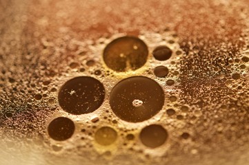 Oil drops on soapy water in macro view with yellowish filter
