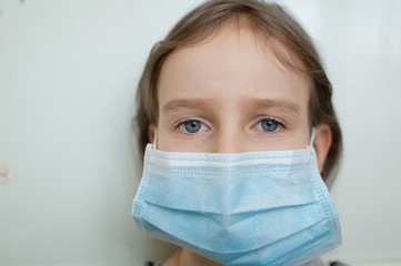 Coronavirus Covid-19 outbreak. Little blonde girl with blue eyes wearing disposable mask for...