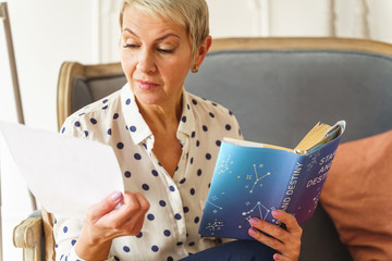 Pleasant blonde woman holding an astrology book