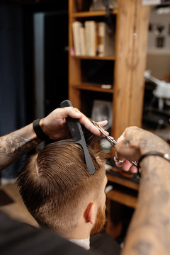 Man cutting hair with scissors and comb