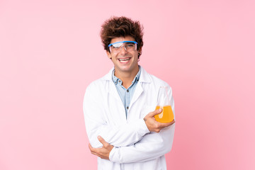 Young caucasian man over isolated pink background with a scientific test tube