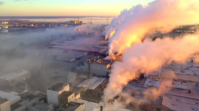 Paper Mill, Factory smokestack emissions at foggy sunrise, beautiful and necessary, yet bad for the environment. moving aerial drone view.