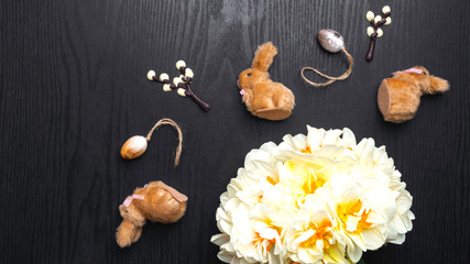 chocolate willow branche, bunnies, narcissus flower on wooden background