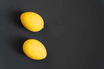 Easter yellow decorated eggs on black paper background. Minimal easter concept. Happy Easter card with copy space for text. Top view, flatlay.
