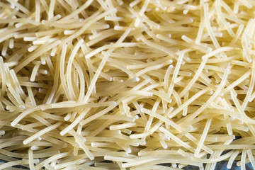 short thin vermicelli on the whole background. texture of dry yellow pasta.
