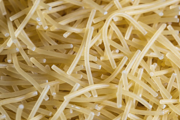 short thin vermicelli on the whole background. texture of dry yellow pasta.