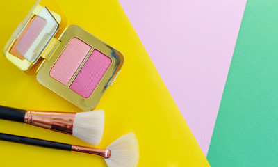 premium makeup brushes, red lipstick, bottle of perfume and blush pads on a bright colorful background, creative cosmetics flat lay
