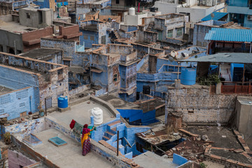 woman washing clothes on rooftop in blue city india