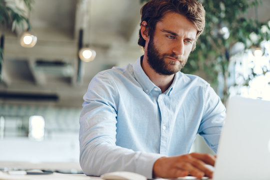 Businessman in shirt working on his laptop in an office. Open space office