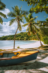 Obraz na płótnie Canvas Boats on exotic beach Takamaka with Palm trees und blue ocean lagoon in background, Mahe island, Seychelles