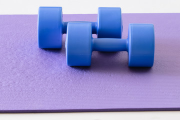 sports ware for gym. Sport concept. Sporting items on purple background or lavender. blue dumbbell on purple mat sport. Space for your text. Sports concept. Sport equipment. Fitness
