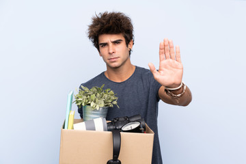 Man making a move while picking up a box full of things making stop gesture with her hand