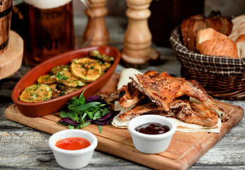 grilled chicken parts served with roasted potato slices and sauces