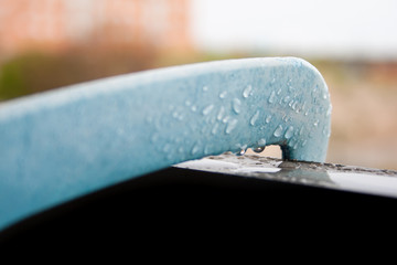 Plastic piece with water drops on the railing of a wet valcon during a rainy day