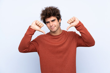 Fototapeta premium Young caucasian man over isolated blue background showing thumb down