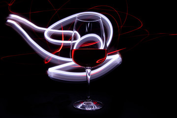 Lights and red wine glass on black background