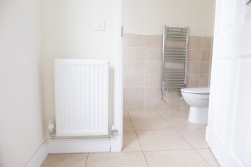 White radiator on wall and ensuite bathroom WC toilet