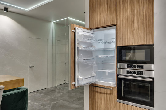 Multifunctional modern kitchen. Built-in appliances. Opened door of the new fridge