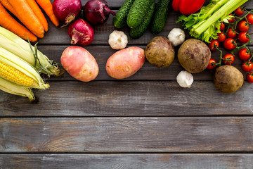 Set of autumn vegetables - potato, cucumber, carrot, greenery - on dark wooden background top-down copy space frame