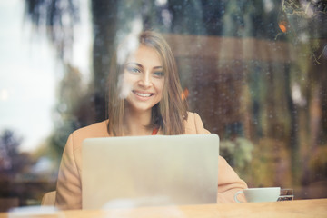 Happy business woman student smiling looking at you with computer in coffee shop