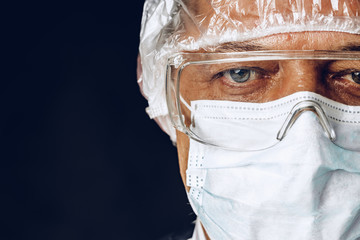Male doctor wearing protective Mask and Goggles. Dark background. Close up