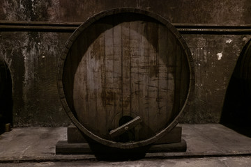Large oak barrel with wine close-up. It stands in an old dark cellar