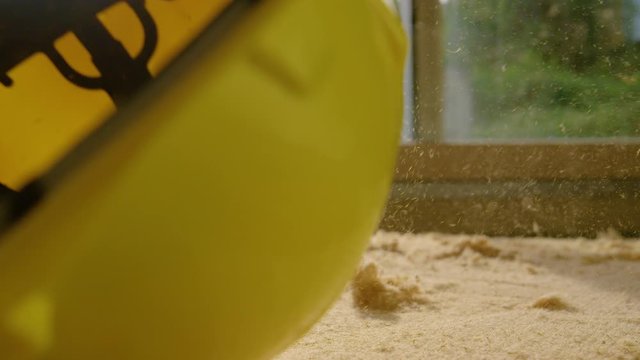 SLOW MOTION, LENS FLARE, CLOSE UP, DOF: Yellow hard hat falls onto a panel of polyurethane insulation lying on the floor of modern house under construction. Bright sunbeams shine on construction site.
