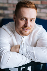 Portrait of handsome young adult man looking at camera, crossed hands.