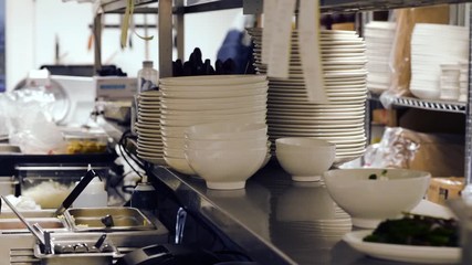 Shelves full of restaurant plates and other kitchenware. Panning video of restaurant kitchen interior.