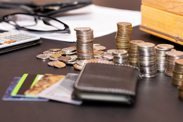 Money, Finance, business growth concept, on the black table ru credit cards, a calculator and a woody piggy Bank for money on the background of coins exposed columns