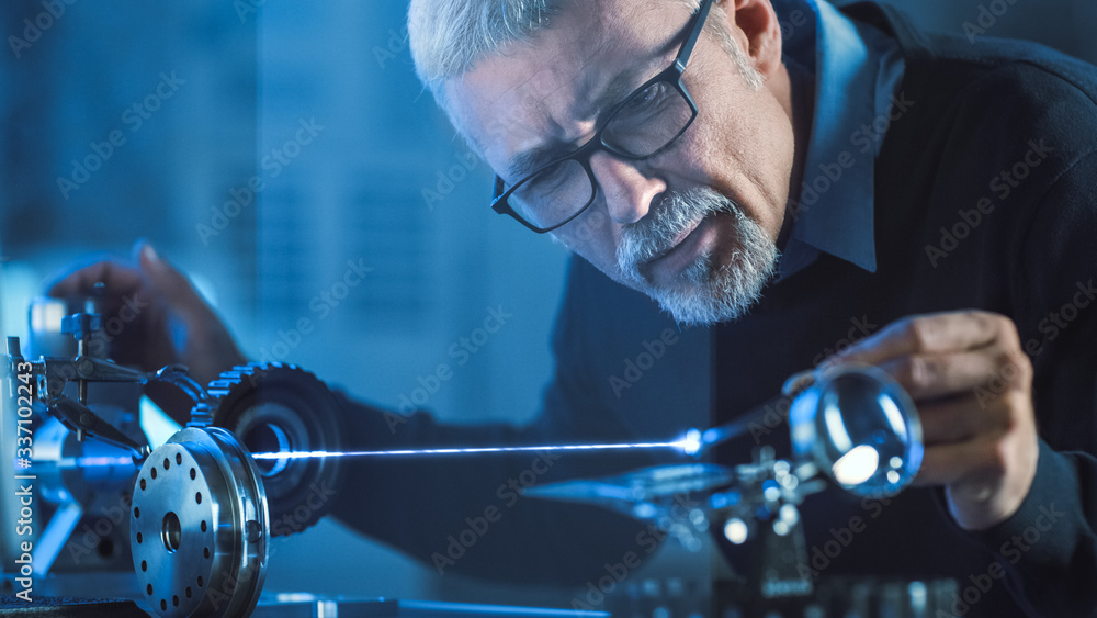 Poster Close-up Portrait of Focused Middle Aged Engineer in Glasses Working with High Precision Laser Equipment, Using Lenses and Testing Optics for Accuracy Required Electronics