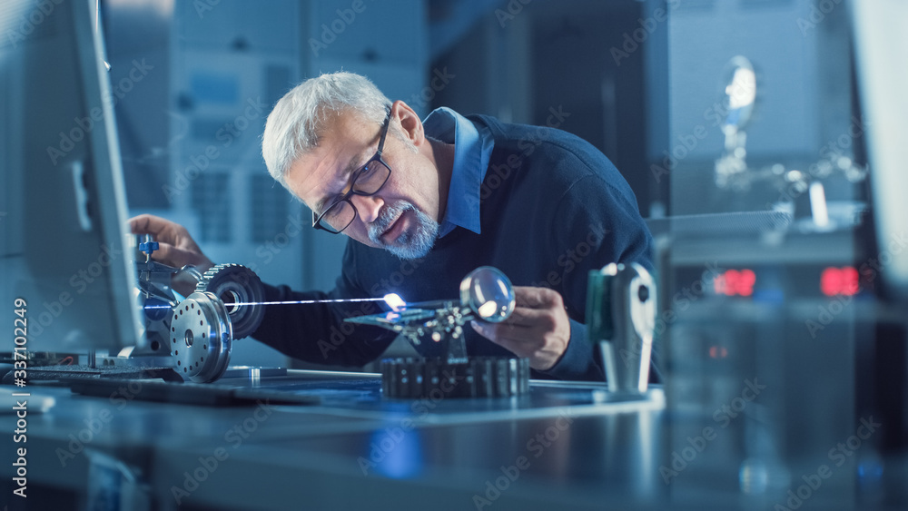 Fototapete portrait of focused middle aged engineer in glasses working with high precision laser equipment, usi