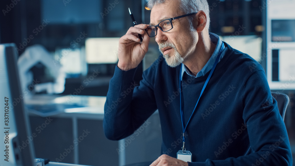 Poster portrait of handsome confused middle aged engineer wearing glasses works on personal computer. in th