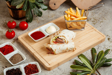 meat wrap in flatbread served with french fries and sauces