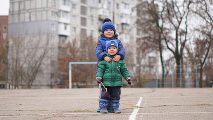 Two little cute boys brothers at a playground on a cloudy day