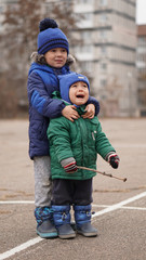 Two little cute boys brothers at a playground on a cloudy day