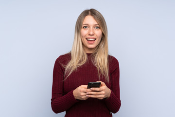 Young blonde woman over isolated blue background surprised and sending a message