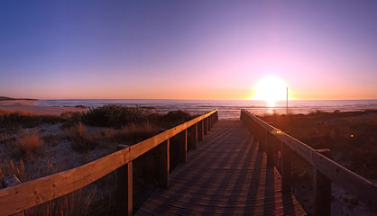 View of the atlantic ocean from a wooden jetty at sunset on a beach in Portugal