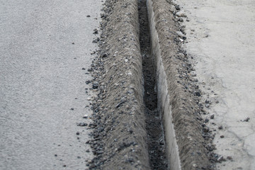 A trench excavation along the curb on the road to replace it