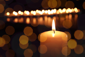 Burning candle on dark background, bokeh effect