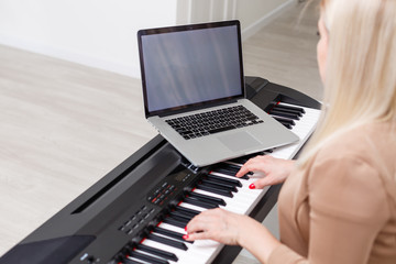 Fototapeta na wymiar woman musician playing classic digital piano at home during online class at home, social distance during quarantine, self-isolation, online education concept