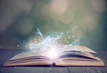 Open book with magic glowing on wooden table. Fairy tale