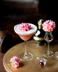 pink cocktail in a long stem glass garnished with pink flowers