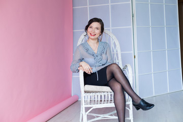 Beautiful fashionable Asian woman sits in a chair