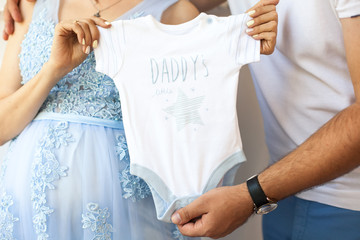 Male and female hands hold baby clothes