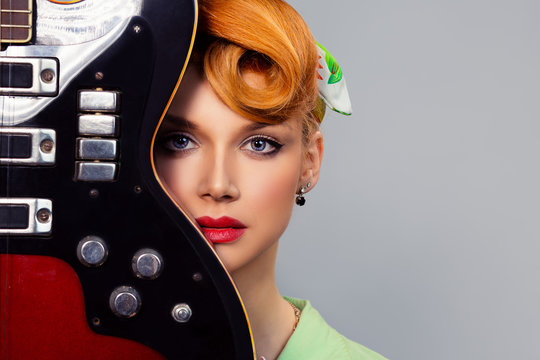 Pretty girl with guitar. pin up hair style retro woman with red head holding electric guitar