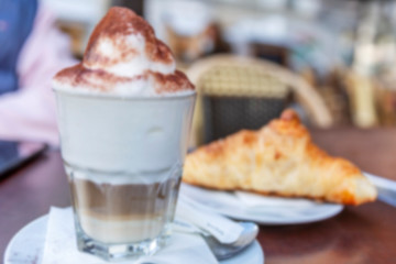 Appetizing cappuccino with croissant on a table in a cafe. Blurred. Background. Time for coffee.