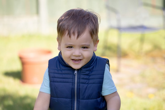 Portrait Of A Little Boy Smiling, Being Outside In A Nice Sunny Day. Garden Background